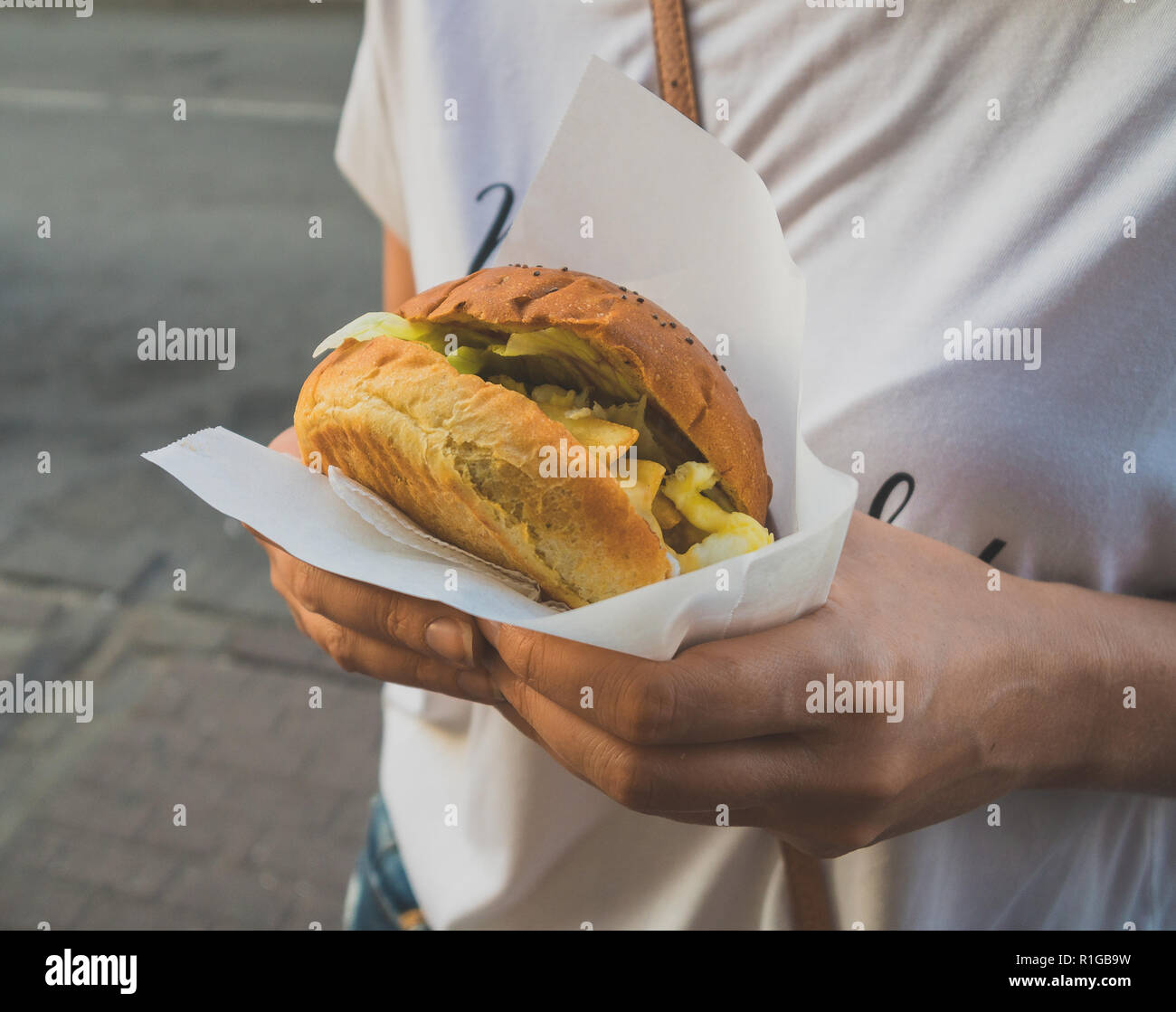 Woman hands holding a hamburger. Street food. Stock Photo