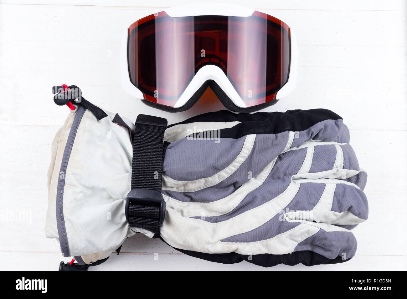 Winter gloves and goggles on white natural wooden table background. Concept of skiing or snowboarding. Flat lay top view. Stock Photo