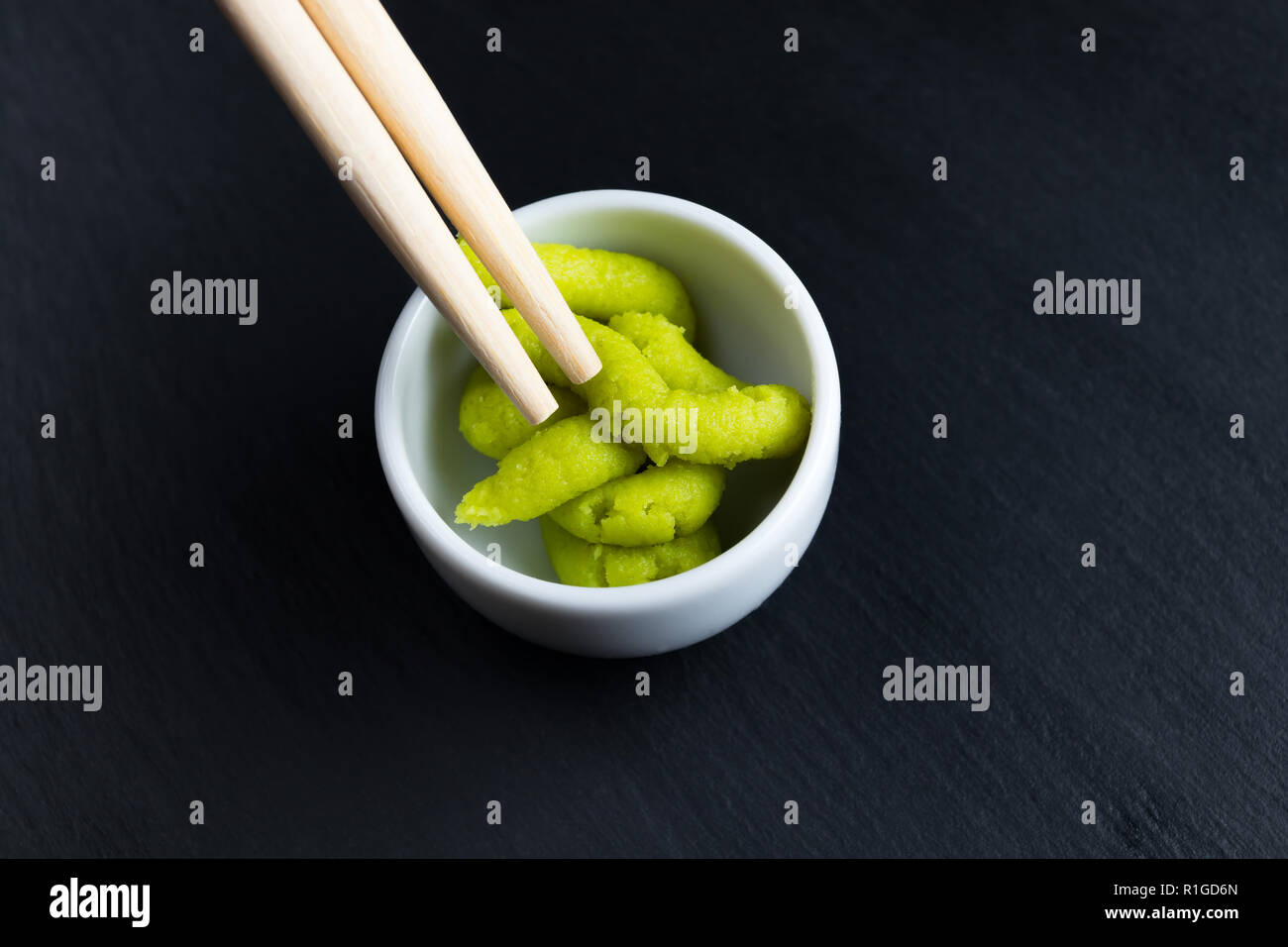Japanese horseradish wasabi in small white bowl with chopsticks on