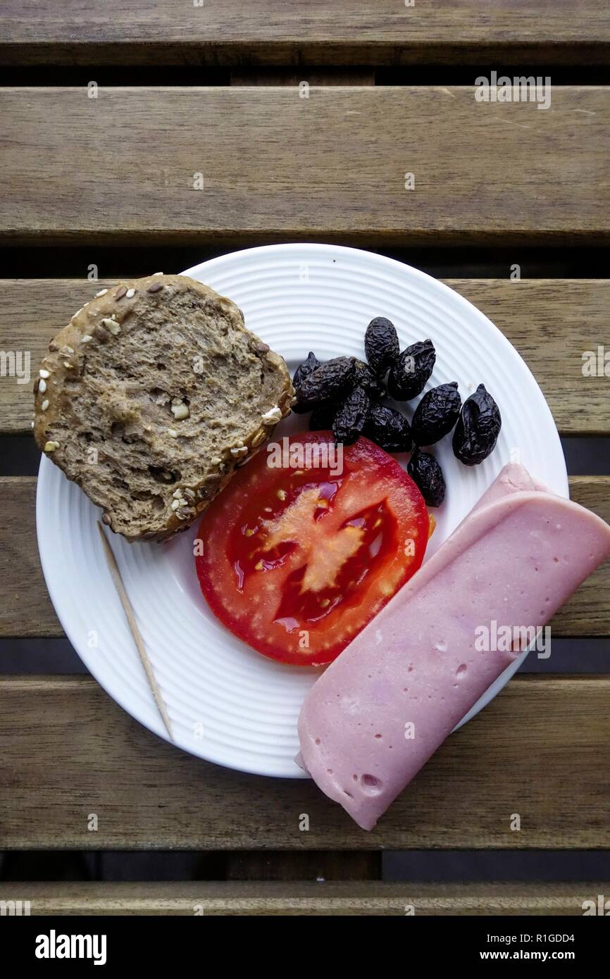 Simple Meze oF Dakos Paximadi Wholewheat Rusk, Tomato, Black Olives and Greek Pariza Slice Meat.  (Finely chopped pork blended with spices.) Stock Photo