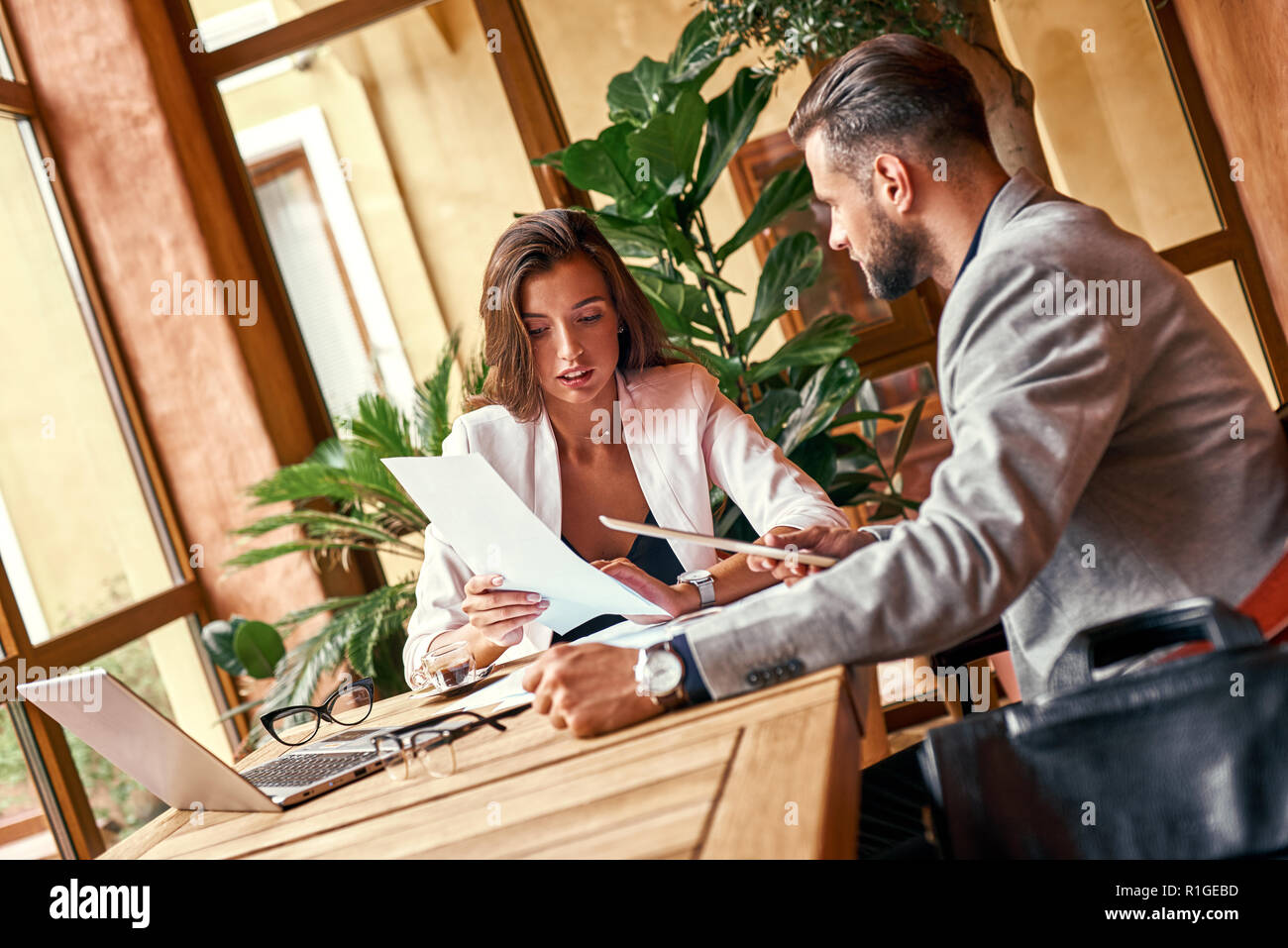 Business lunch. Business people sitting at table at restaurant woman explaining project idea to man holding digital tablet Stock Photo