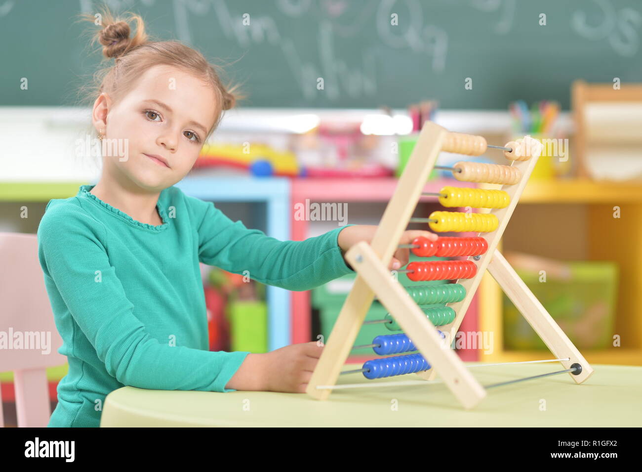 Portrait of little girl sitting and counting on abacus Stock Photo