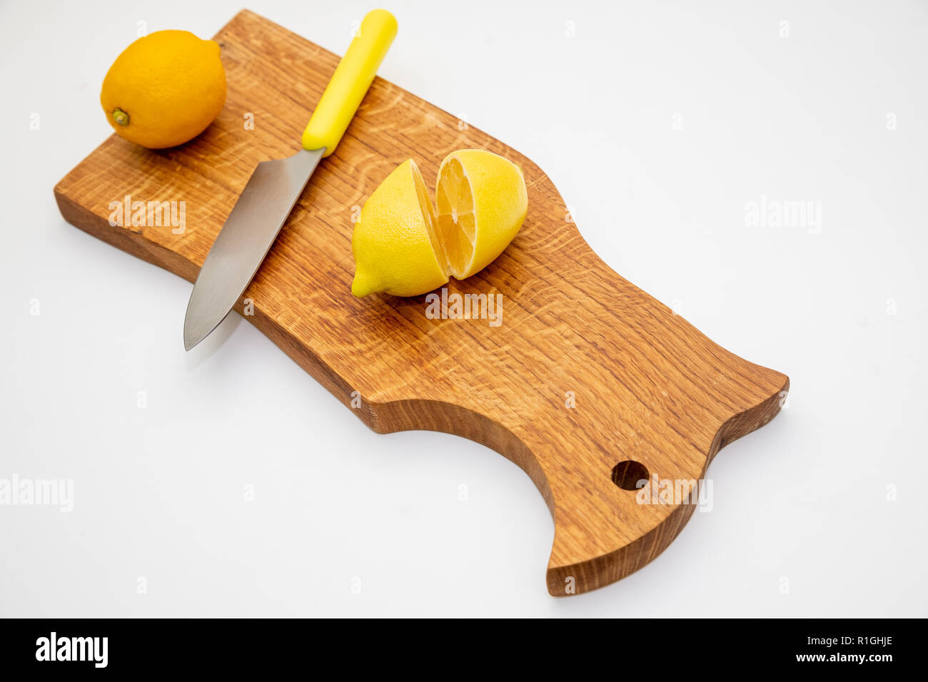 Sliced fresh lemon over chopping board.environmentally friendly, ecological products.prevention of colds.Sliced and whole lemons on cutting board with a knife .Copy space Stock Photo
