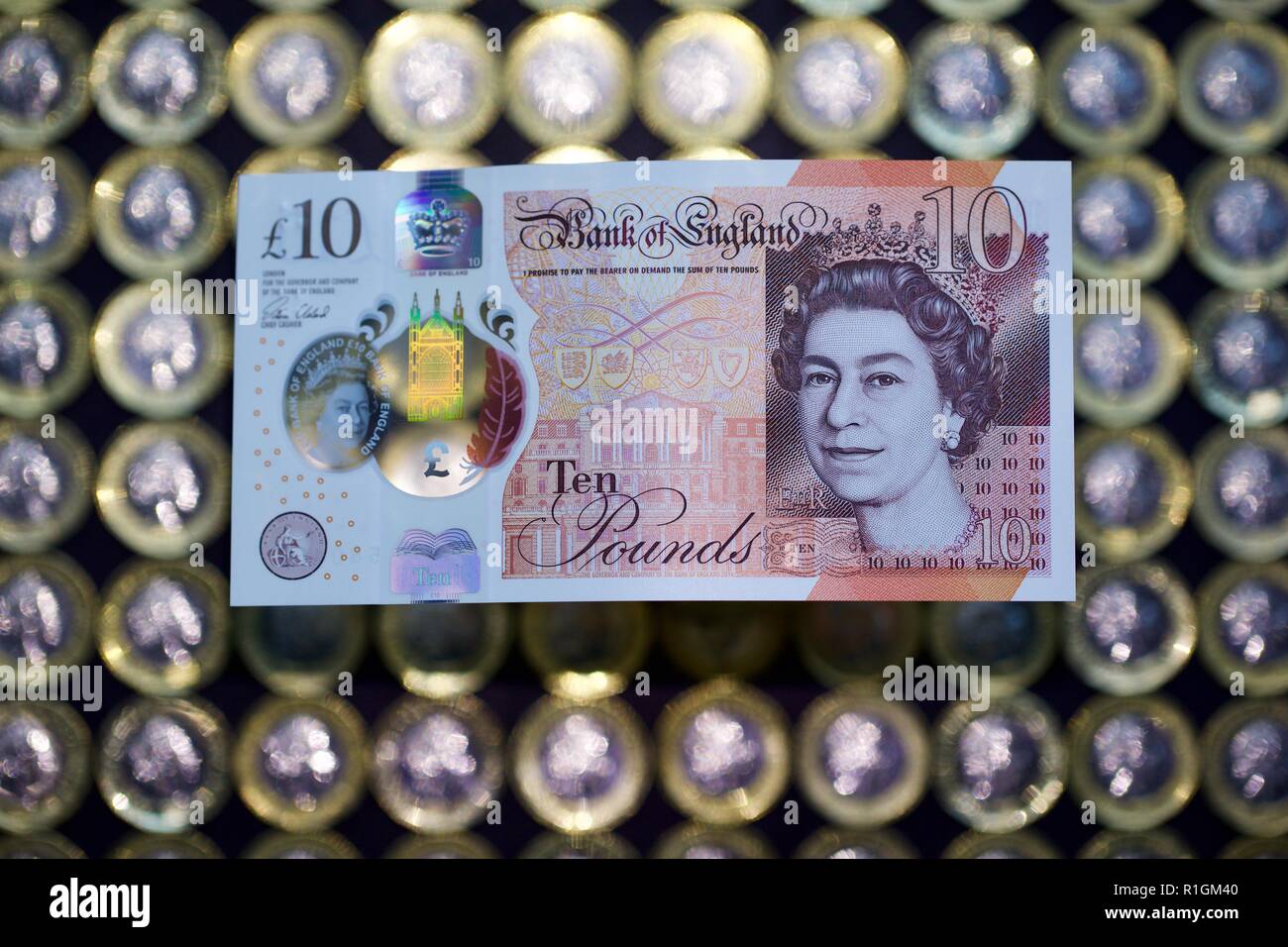 The new polymer £10 note, featuring Jane Austen, with the new £1 coins in the background Stock Photo