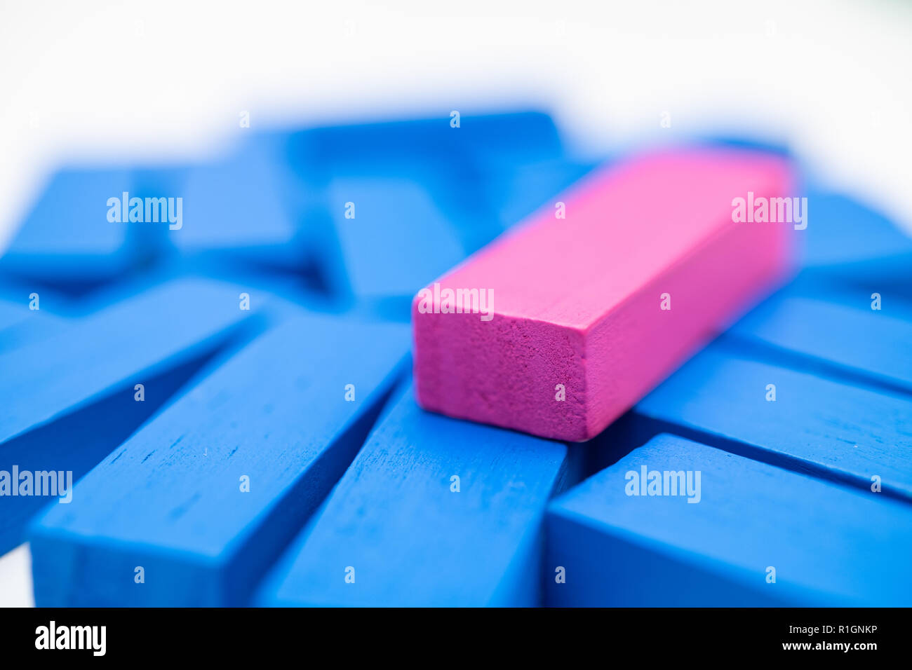 Large group of blue bricks toy game with one different pink one on top