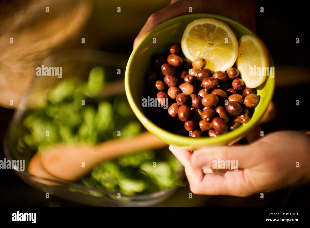 Hands holding a bowl of olives and two lemon slices. Stock Photo