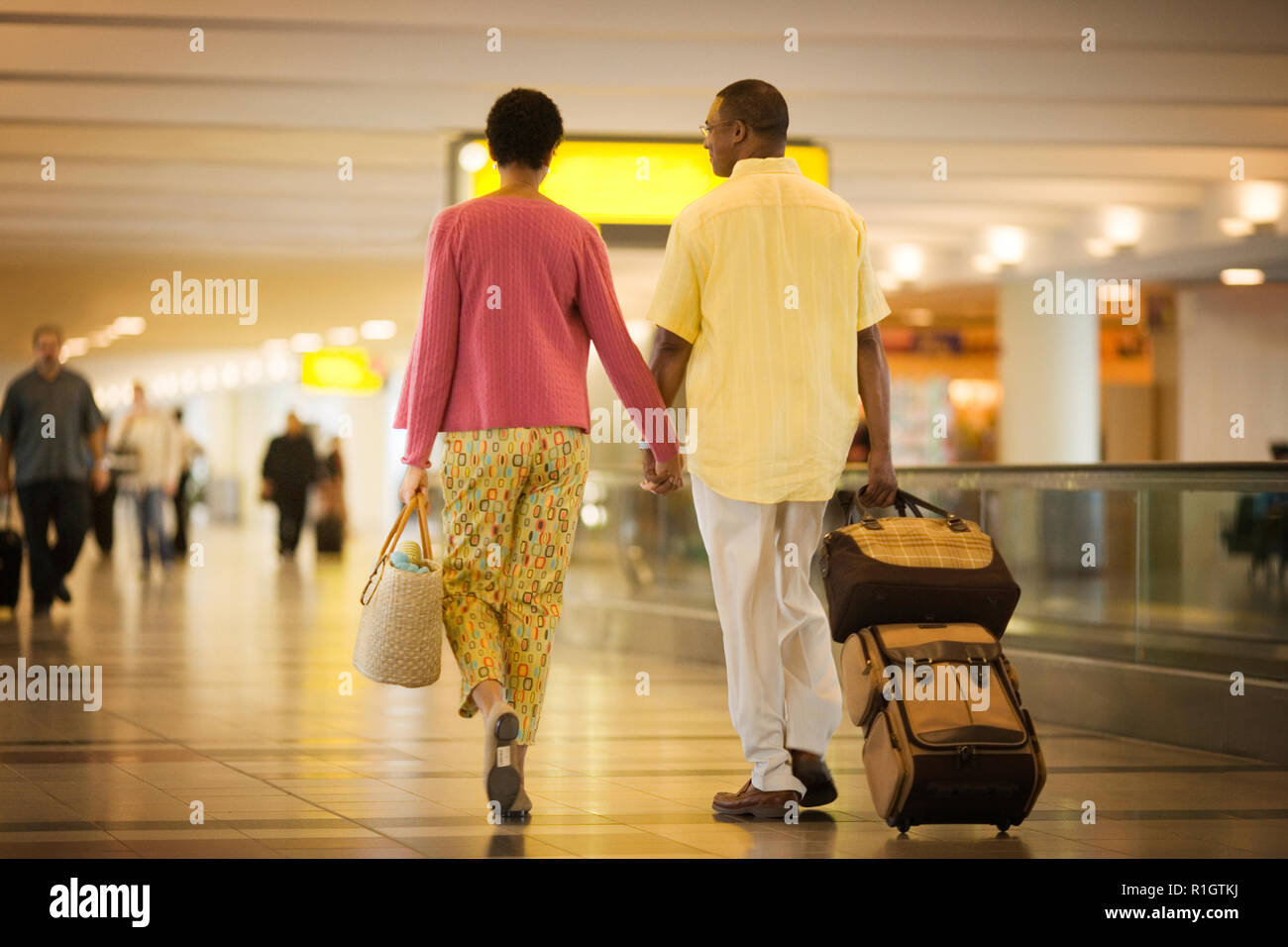 Mid-adult couple walking through an airport terminal Stock Photo - Alamy