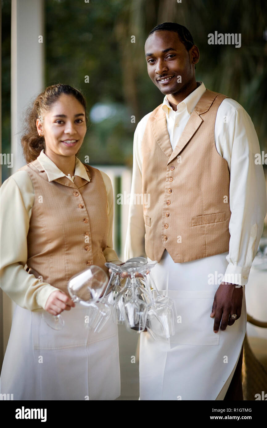 Portrait of young adult male and female wait staff holding wine glasses. Stock Photo