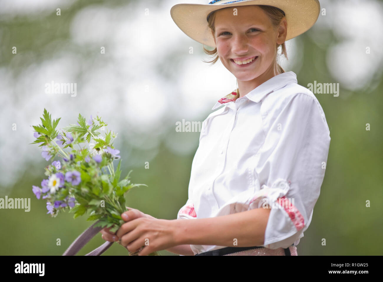 Girl on horseback holding bunch of flowers Stock Photo