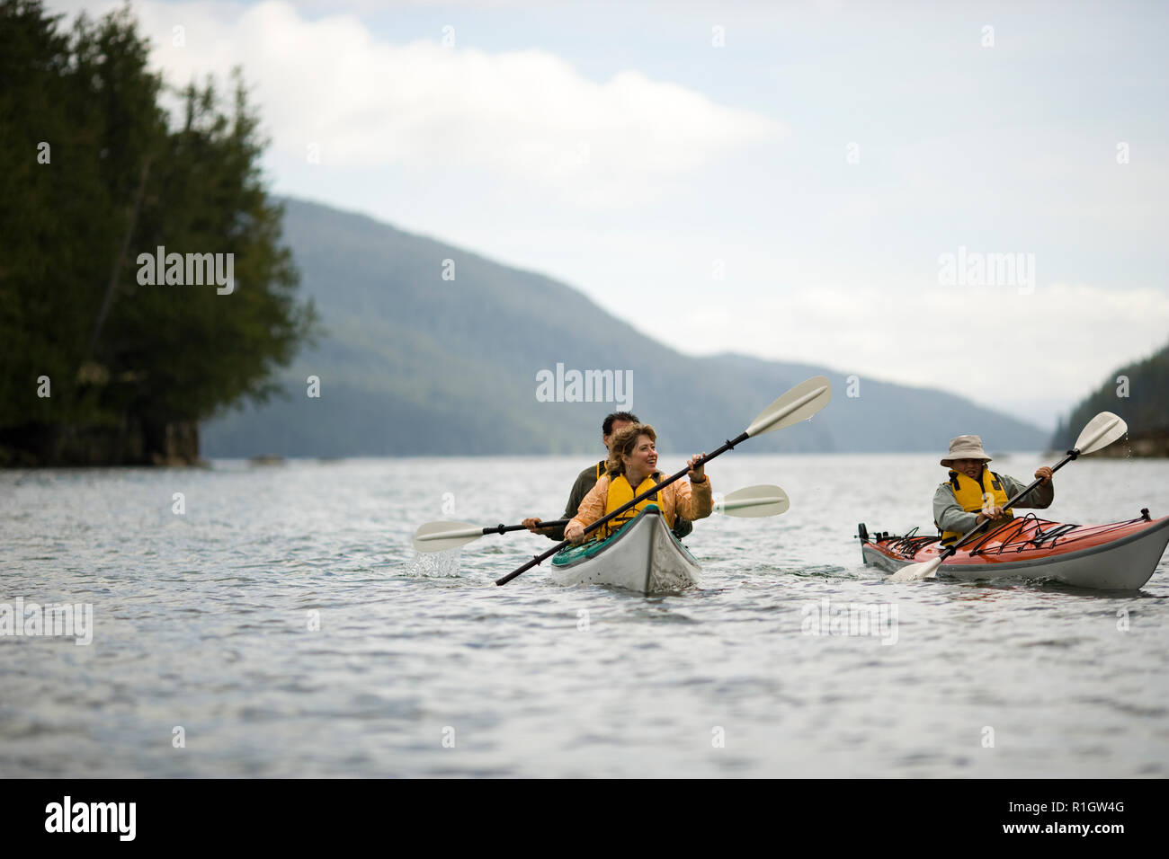 Mid-adult couple kayaking with their teenage son on a lake. Stock Photo