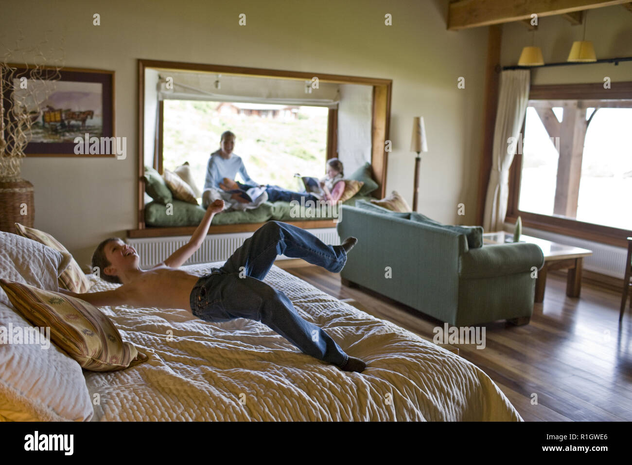 Young Boy Bouncing On A Bed In A Bedroom Stock Photo
