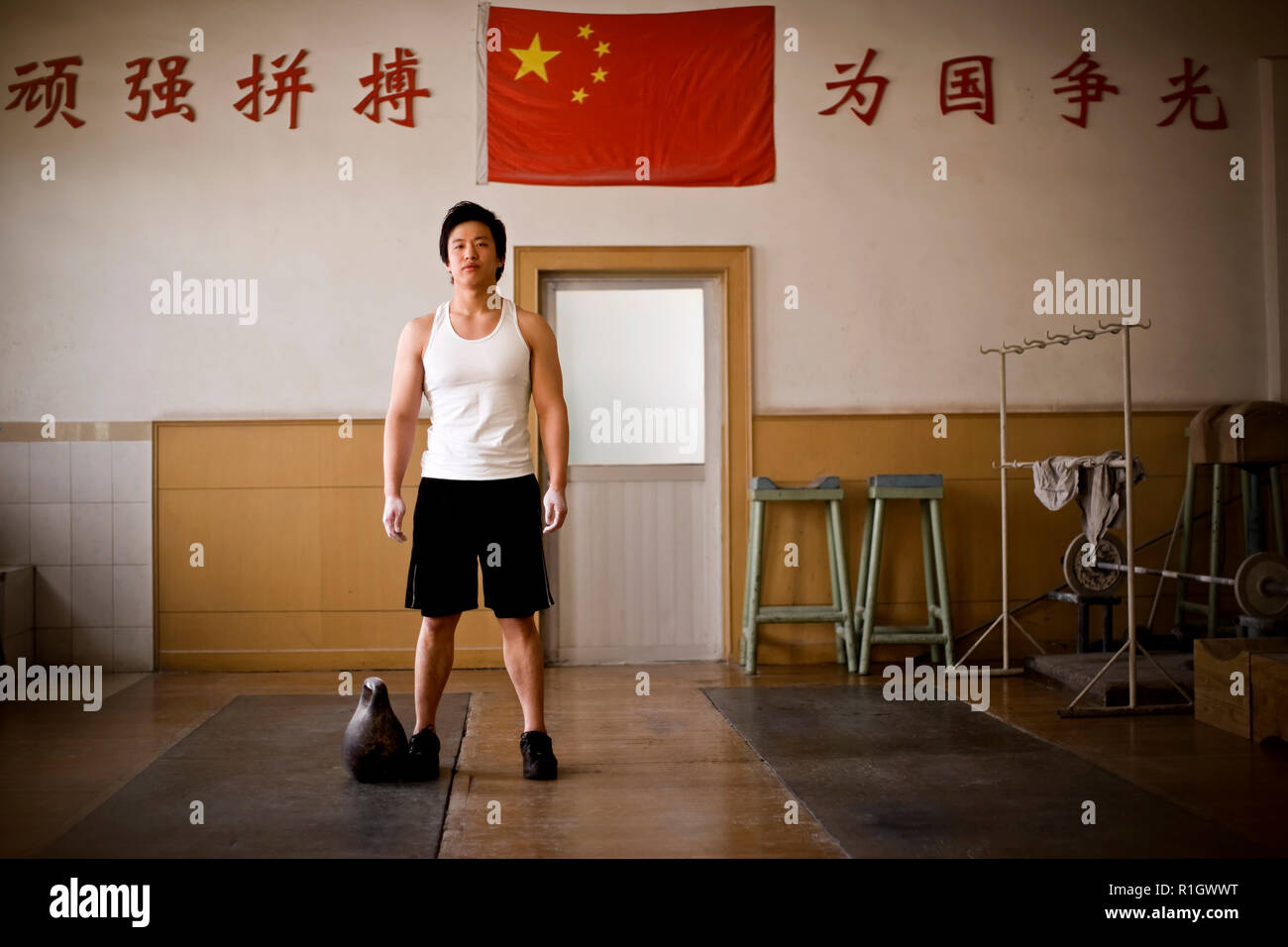 Young adult boy standing beside a kettle bell in a gym. Stock Photo