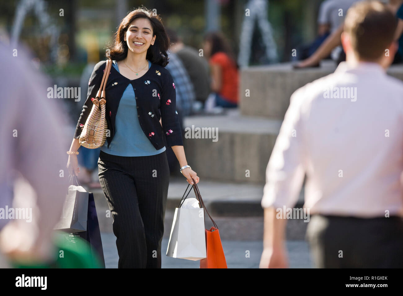 Smiling mid-adult woman carrying shopping bags while walking through the city. Stock Photo