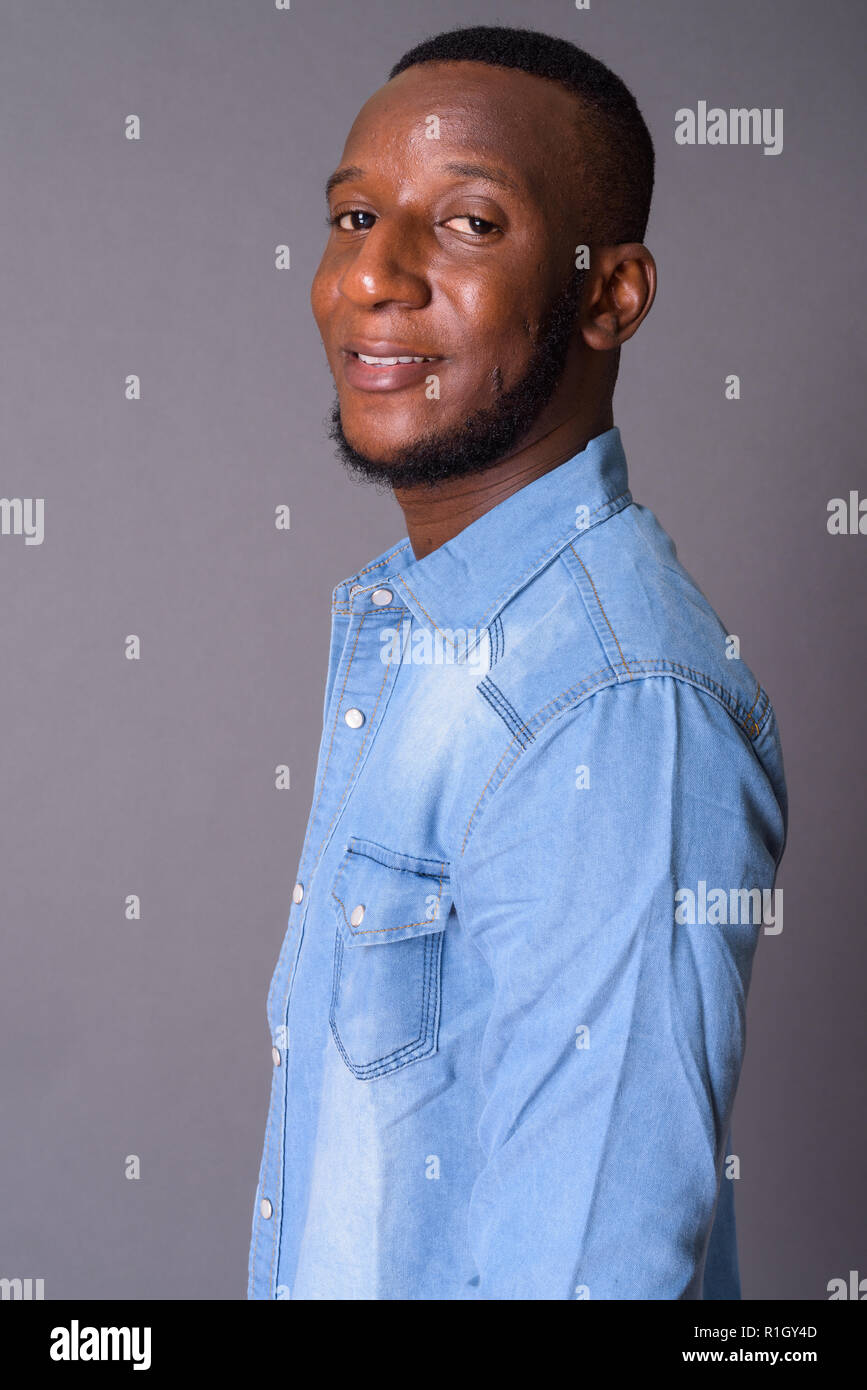 Young handsome African man with short hair against gray backgrou Stock