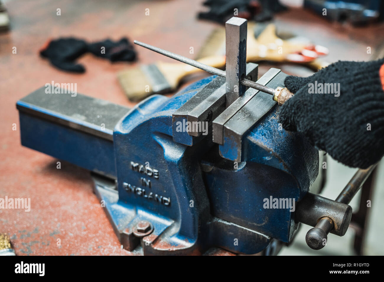 Engineering student file a metal in workshop class Stock Photo - Alamy