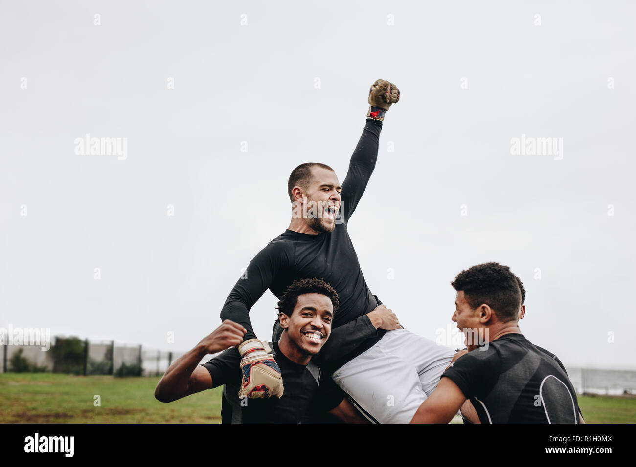 Teammates lifting goalkeeper on their shoulders and celebrating success
