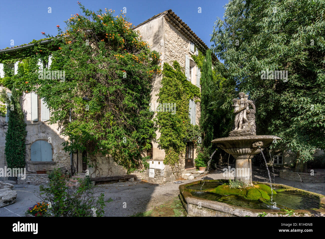 Fountain in Saignon, facade with wild wine in autumn, Provence, France Stock Photo