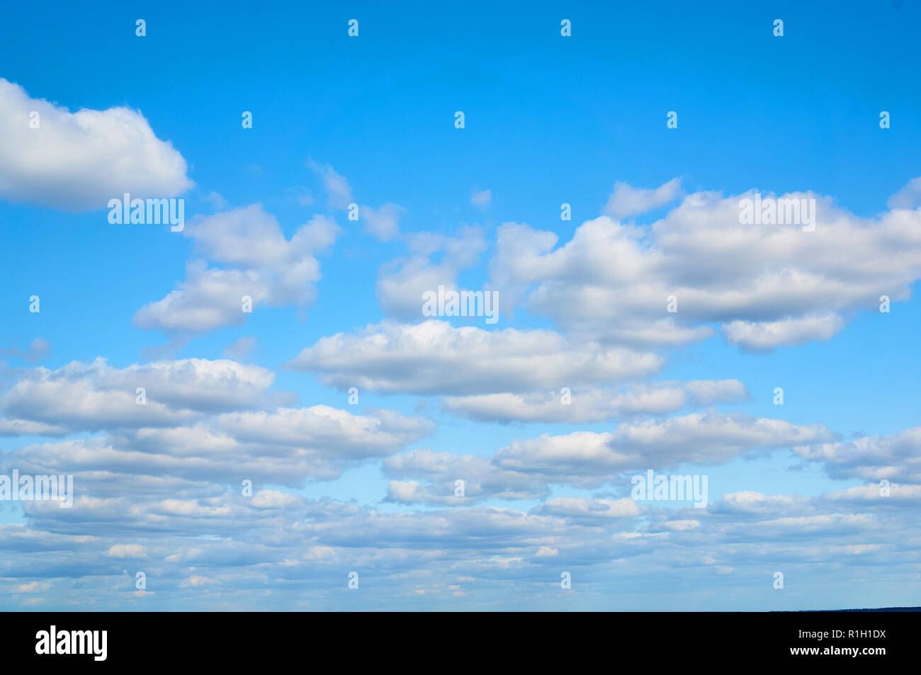 Wavy, porous curly clouds on the blue sky. Nature background. Stock Photo