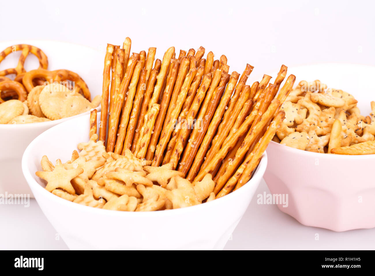 Different salted crackers in bowls on white background. Stock Photo