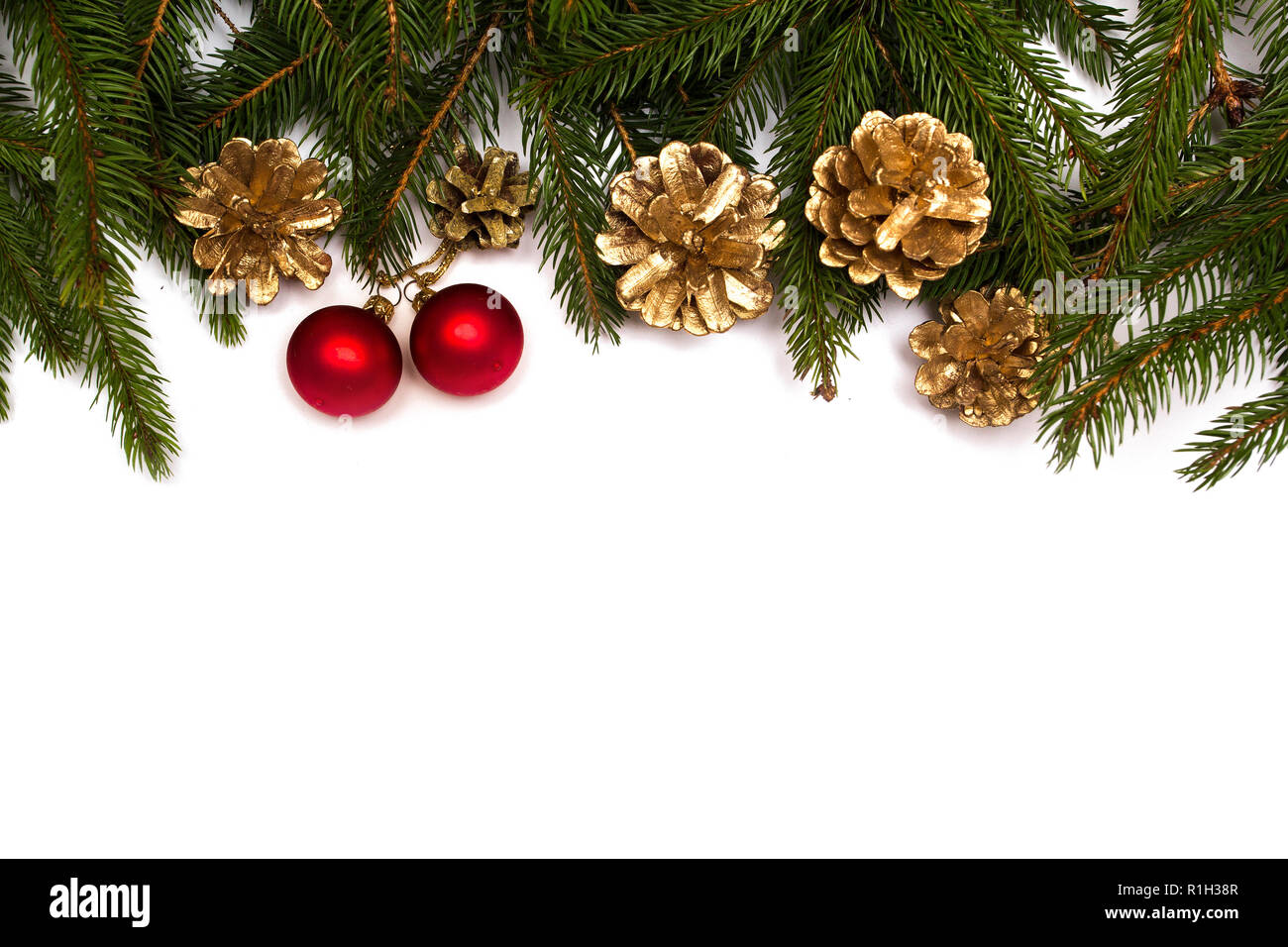 Christmas tree branches with red baubles and gold cones on white background. Stock Photo