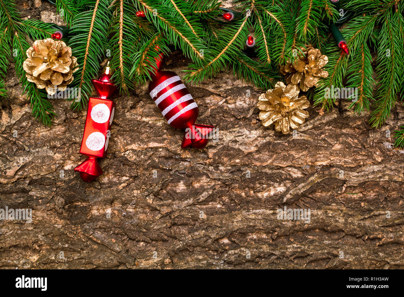 Christmas tree branches with gold cones, baubles and lights on wooden table. . Copy space Stock Photo