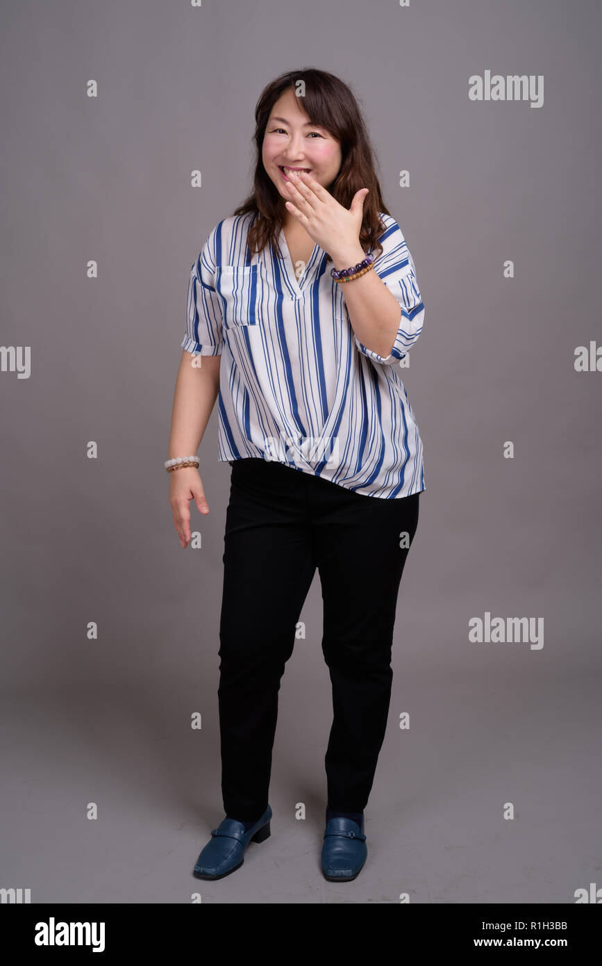 Full length portrait of Japanese businesswoman against gray background Stock Photo