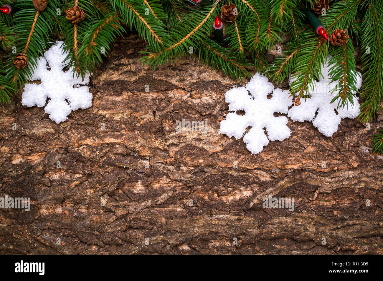 Christmas tree branches with snowflake baubles and lights on wooden background. Stock Photo