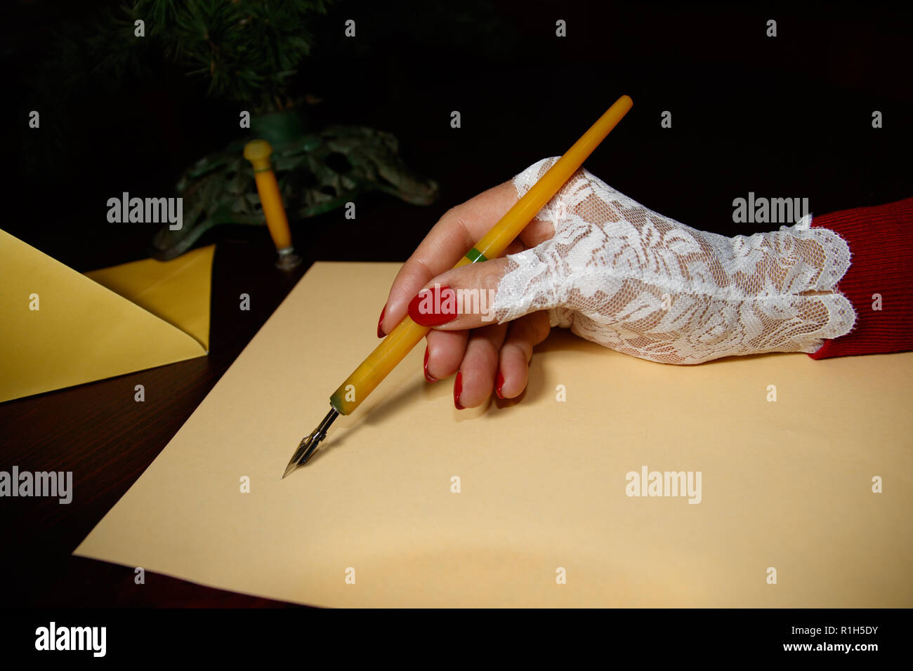 Lady at the age writes letter with quill on yellow paper Stock Photo