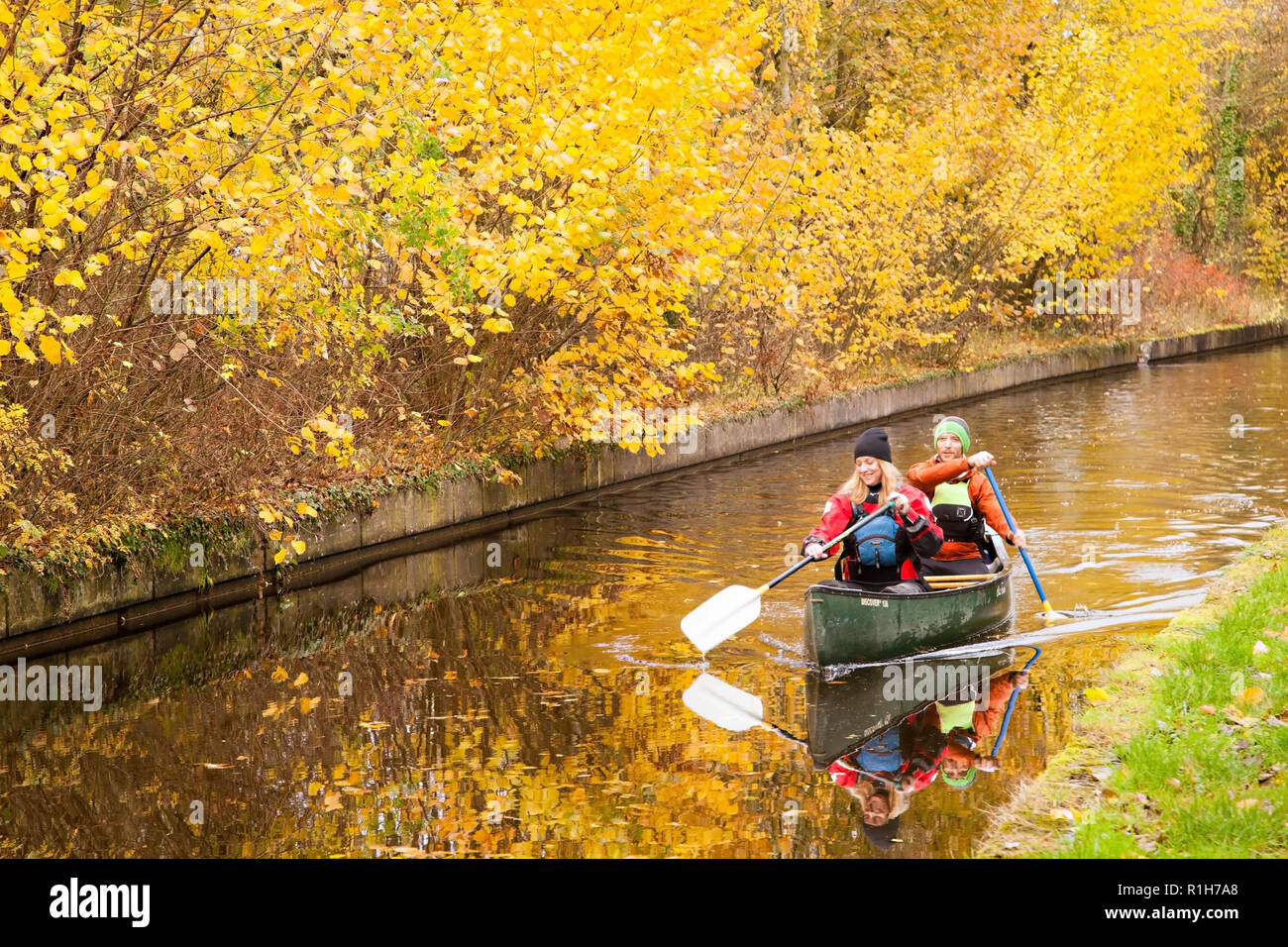 Man and woman canoeing on the 46 mile long Llangollen branch of the Shropshire union canal with glorious Autumn colours in the trees along the towpath Stock Photo