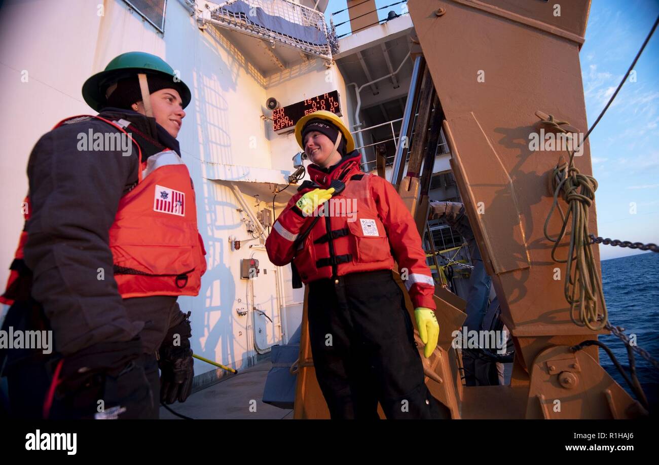 ARCTIC OCEAN - U.S. Merchant Marine Academy Cadet Taylor Crisci (left) and U.S. Coast Guard Petty Officer 2nd Class Shannon Eubanks talk after deploying a series of sensors into the Chukchi Sea from the U.S. Coast Guard Cutter Healy (WAGB-20) Wednesday, Sept. 19, 2018, approximately 100 miles northwest of Barrow, Alaska. When classes aren't in session, MMA cadets spend their summers aboard operational units to gain at-sea experience before they graduate. Approximately 30 scientists are aboard the Healy deploying sensors and autonomous submarines in the Arctic to study stratified ocean dynamics Stock Photo