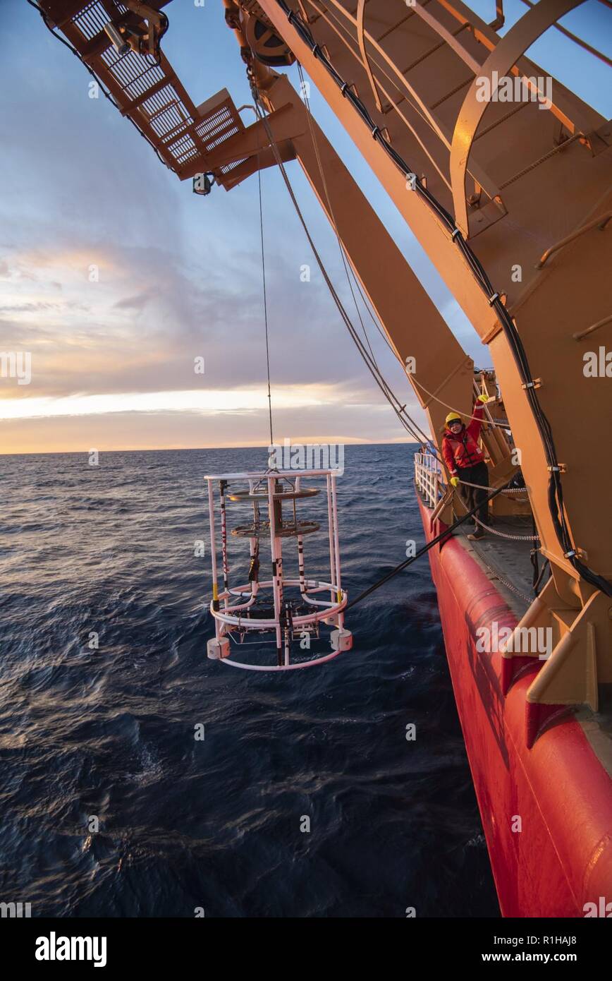 ARCTIC OCEAN - U.S. Coast Guard Petty Officer 2nd Class Shannon Eubanks uses hand signals to tell a crane operator to lower a scientific device used to measure conductivity, temperature and depth into the water Wednesday, Sept. 19, 2018, aboard the Coast Guard Cutter Healy (WAGB-20) approximately 100 miles northwest of Barrow, Alaska, in the Chukchi Sea. Approximately 30 scientists are aboard the Healy deploying sensors and autonomous submarines in the Arctic to study stratified ocean dynamics and how environmental factors affect the water below the ice surface for the Office of Naval Research Stock Photo