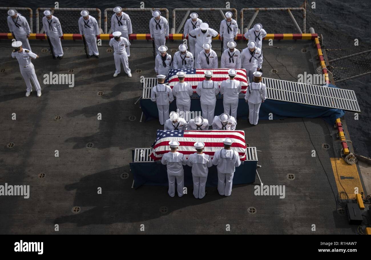 PACIFIC OCEAN (Sept. 19, 2018) Sailors, assigned to the amphibious assault ship USS Bonhomme Richard (LHD 6), bow their heads in prayer during a burial at sea ceremony held on the ship’s starboard aircraft elevator. Bonhomme Richard is currently underway in the U.S. 3rd Fleet area of operations. Stock Photo