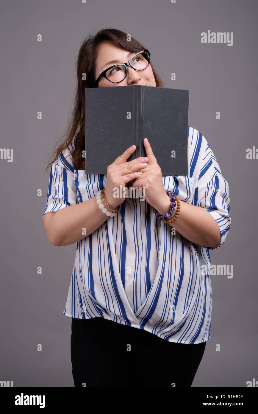 Asian businesswoman holding book against gray background Stock Photo
