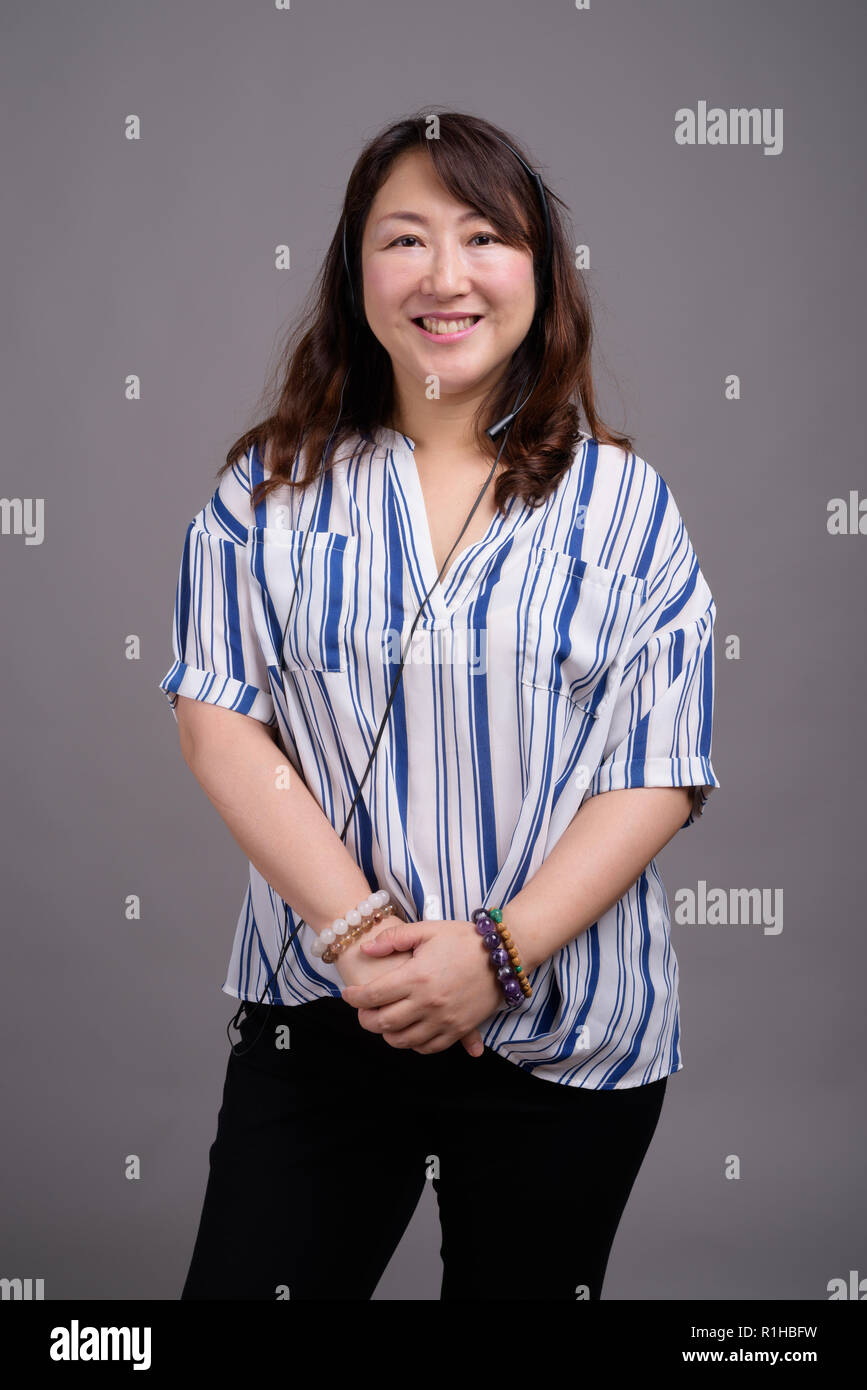 Mature beautiful Asian businesswoman against gray background Stock Photo