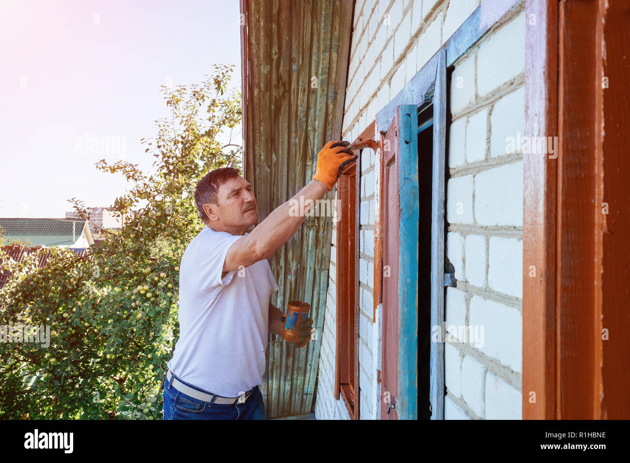 Painter painting the windows of a exterior house Stock Photo