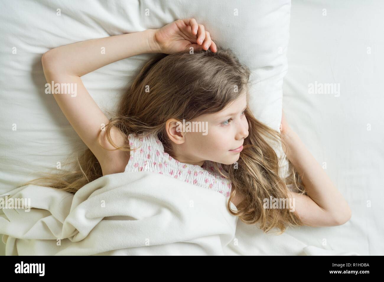 good morning child girl blonde with long wavy hair wakes up lying
