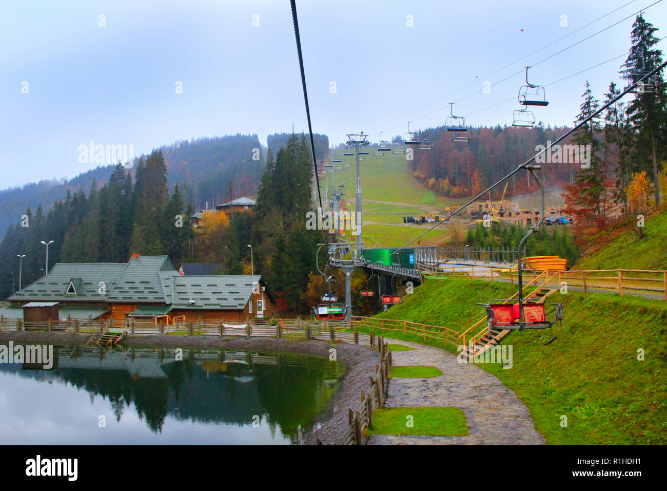 Picturesque lake and tourist houses in ukrainian ski Bukovel. Landscape with mountain lake in resort town. Mountains in resort village Stock Photo