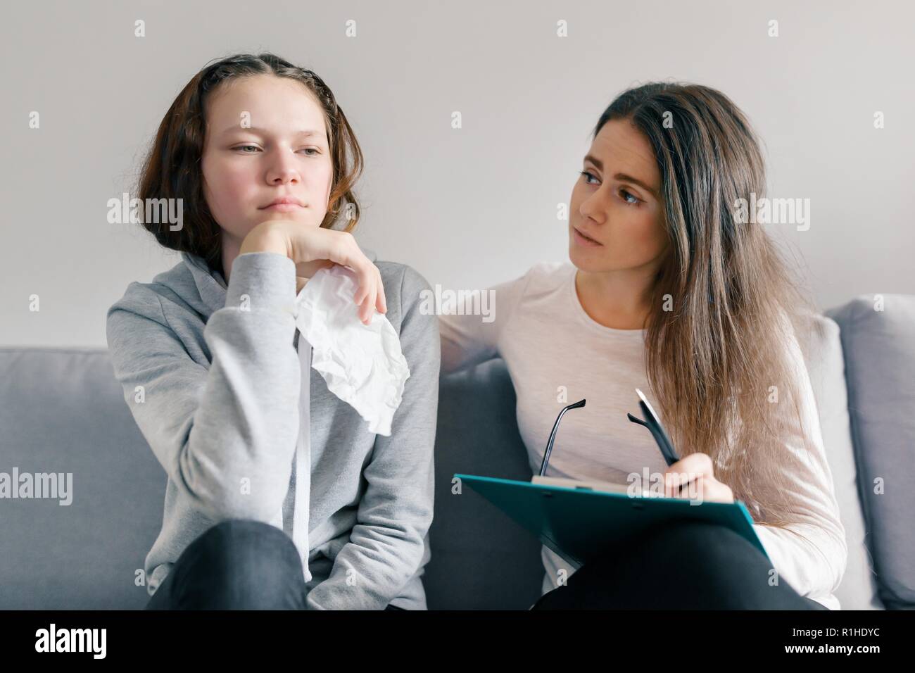 Professional child psychologist talking with teenager girl in office, girl crying. Stock Photo