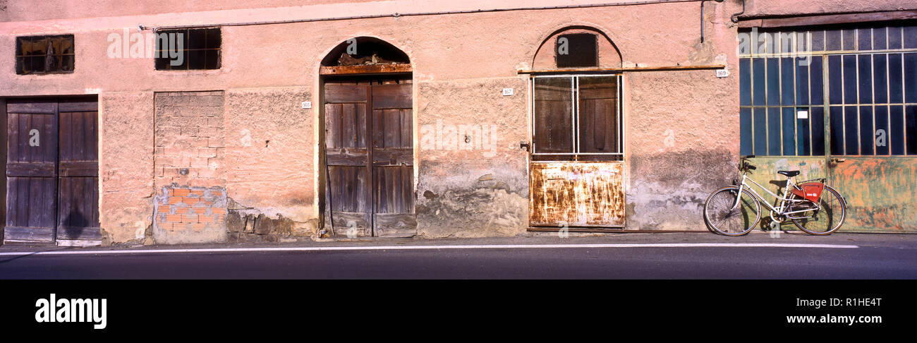 A panoramic view of an old industrial building in Tuscany with bicycle parked outside. Stock Photo