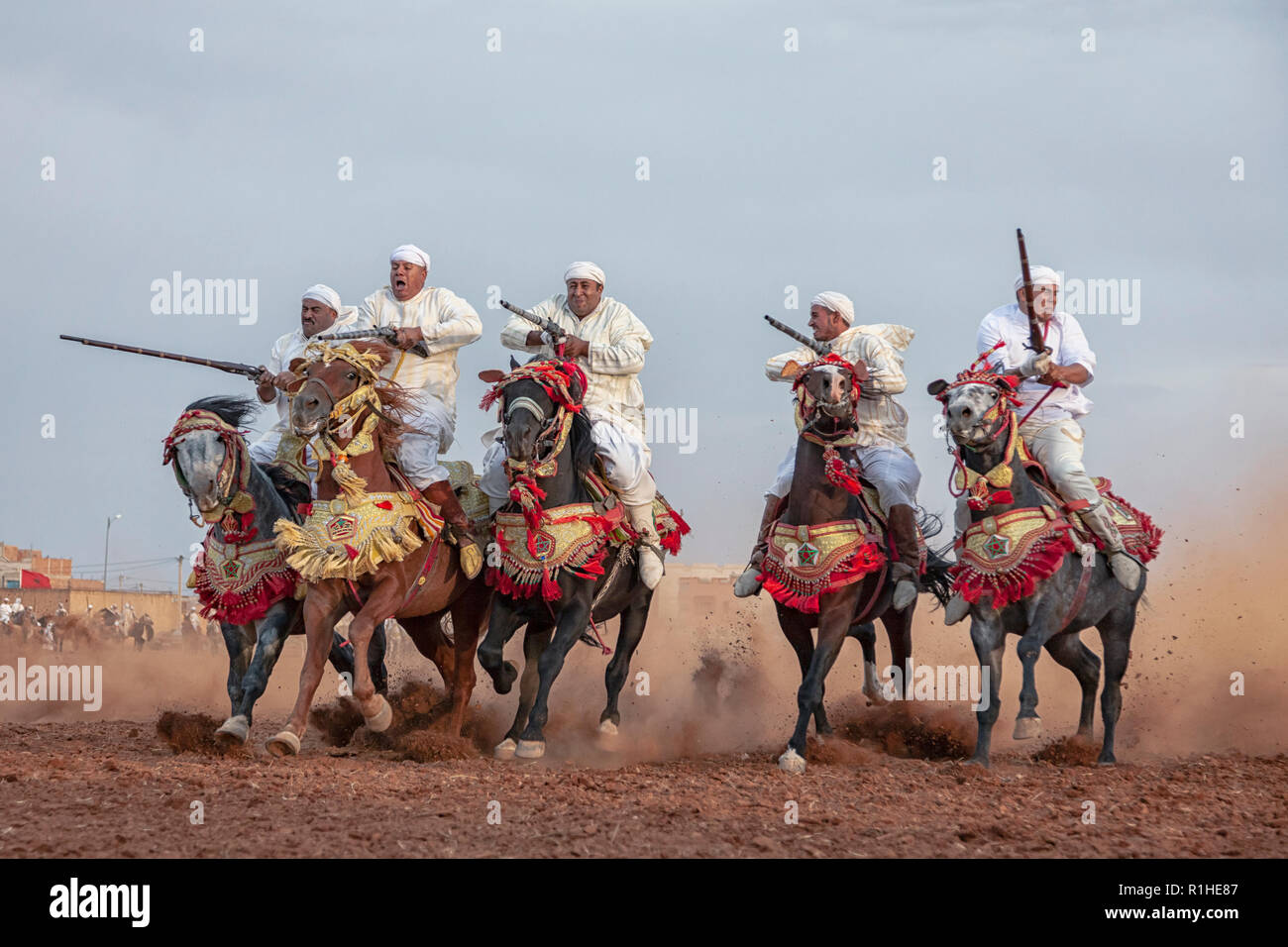 a group of horse riders, wearing traditional clothes and charging along a straight path in a show called Tbouria or Fantasia Stock Photo