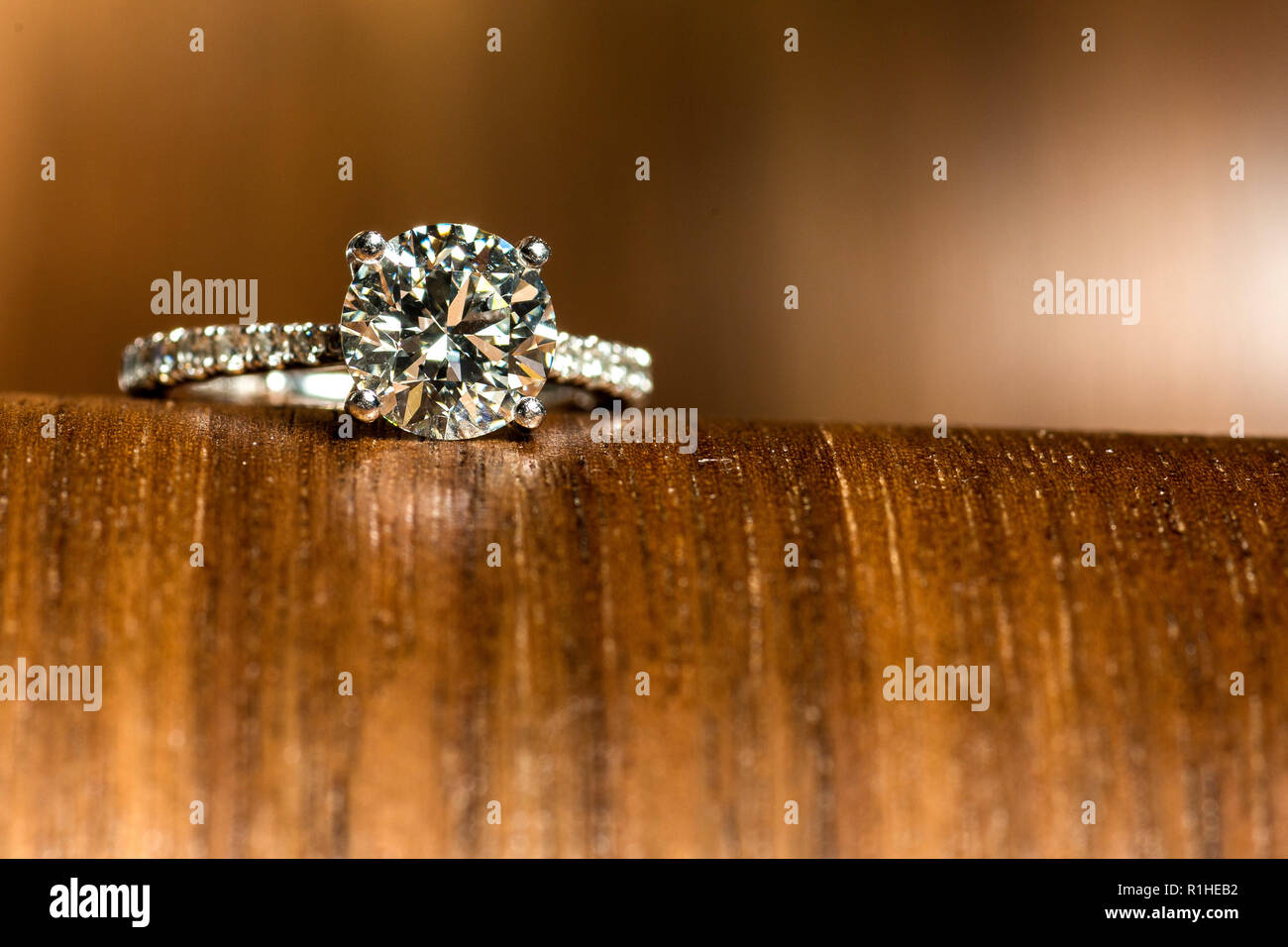 Engagement Ring On Top Of Wooden Cliff, Isolated On Brown Background Stock Photo