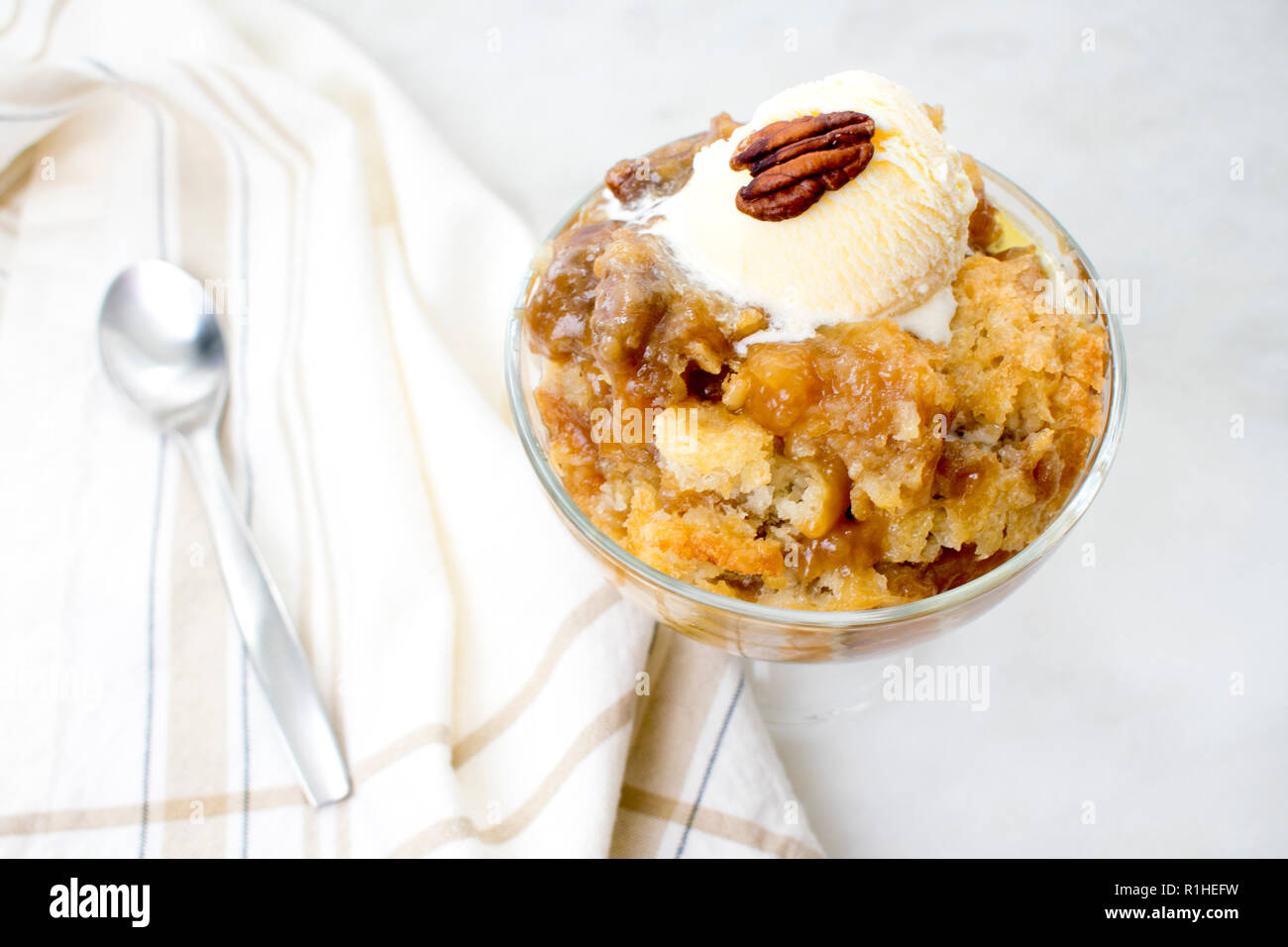 Pecan Cobbler with Vanilla Ice Cream: A dish of southern pecan cobbler in a glass dessert bowl with a spoon Stock Photo