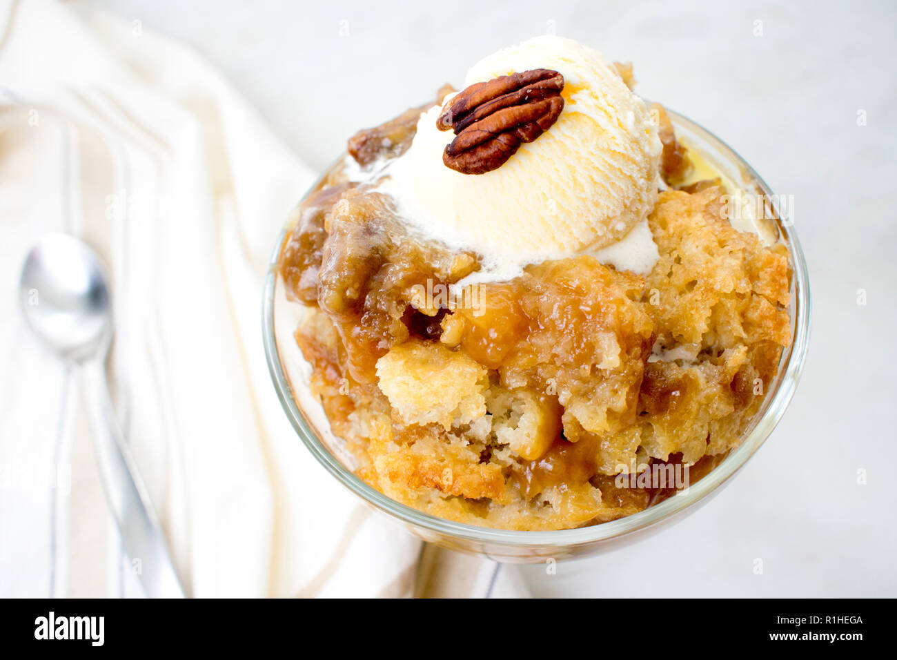 Pecan Cobbler with Vanilla Ice Cream: A dish of southern pecan cobbler in a glass dessert bowl with a spoon Stock Photo