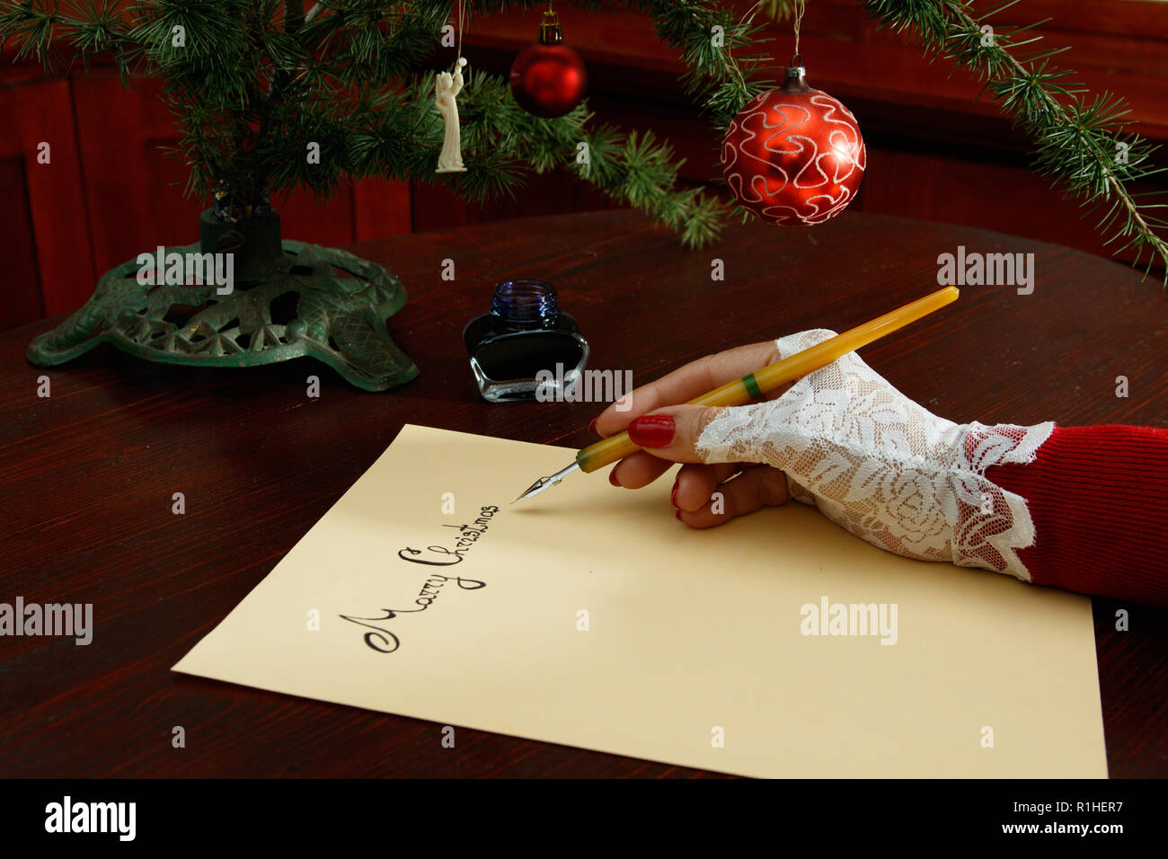 Lady writing christmas greeting card on wooden table Stock Photo