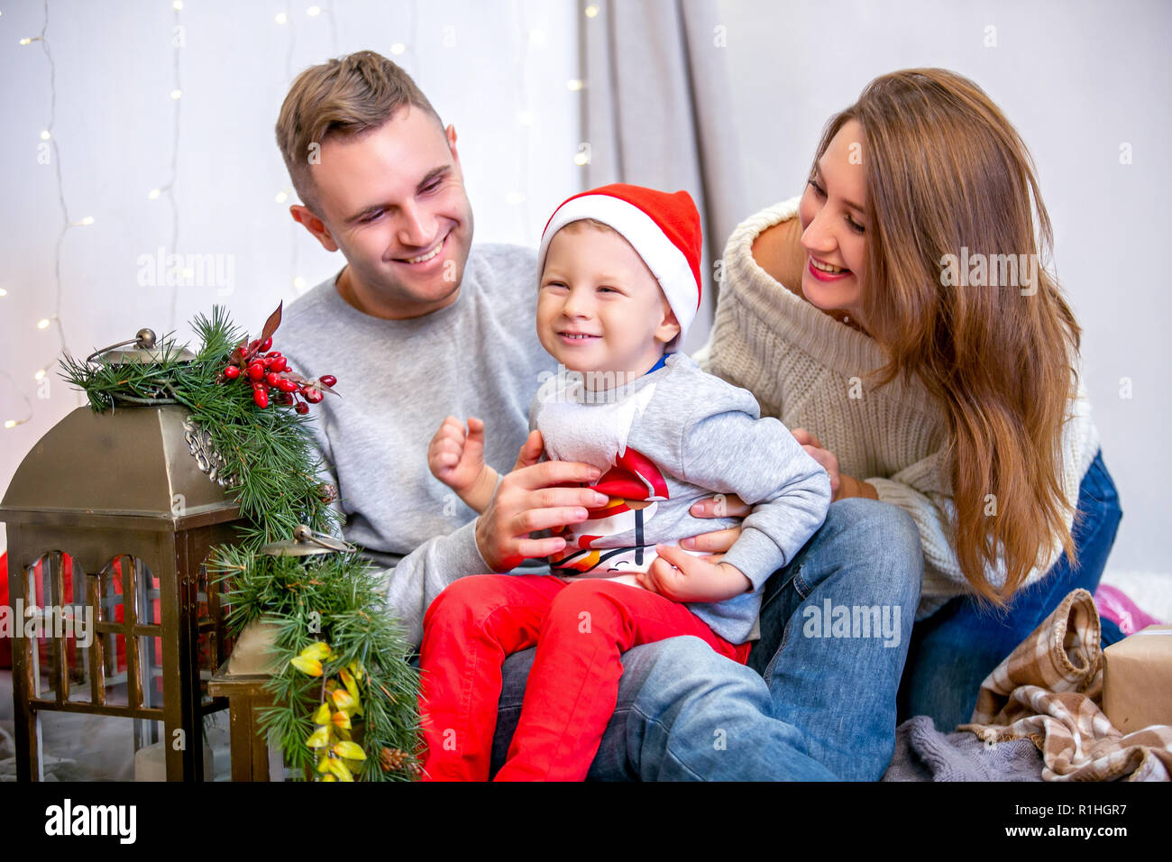 Happy family, father, mother and son, in the morning in bedroom decorated for Christmas. They open presents and have fun. New Year's and Christmas theme. Holiday mood Stock Photo