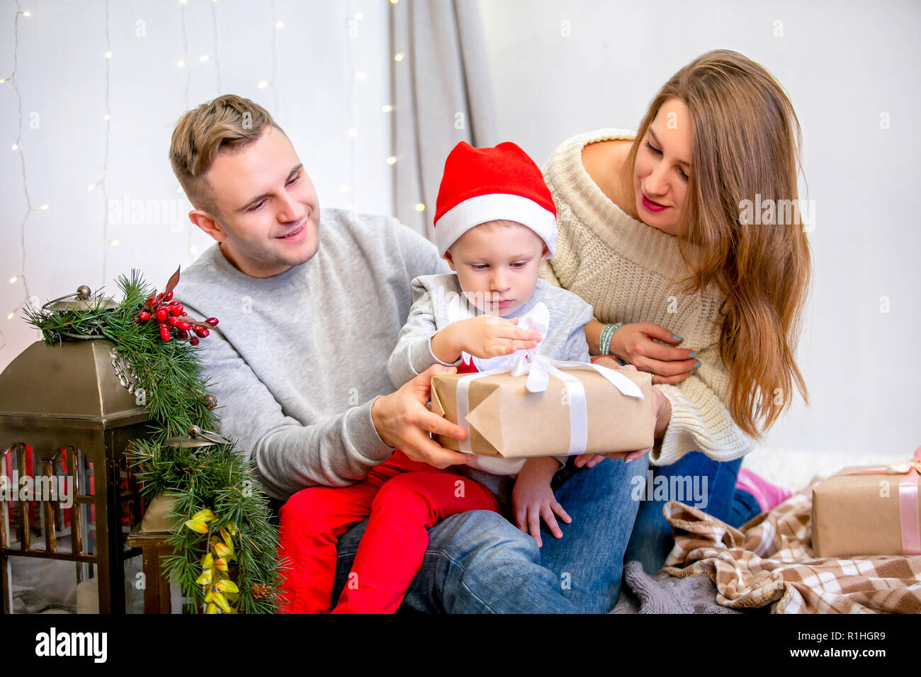 Happy family, father, mother and son, in the morning in bedroom decorated for Christmas. They open presents and have fun. New Year's and Christmas theme. Holiday mood Stock Photo