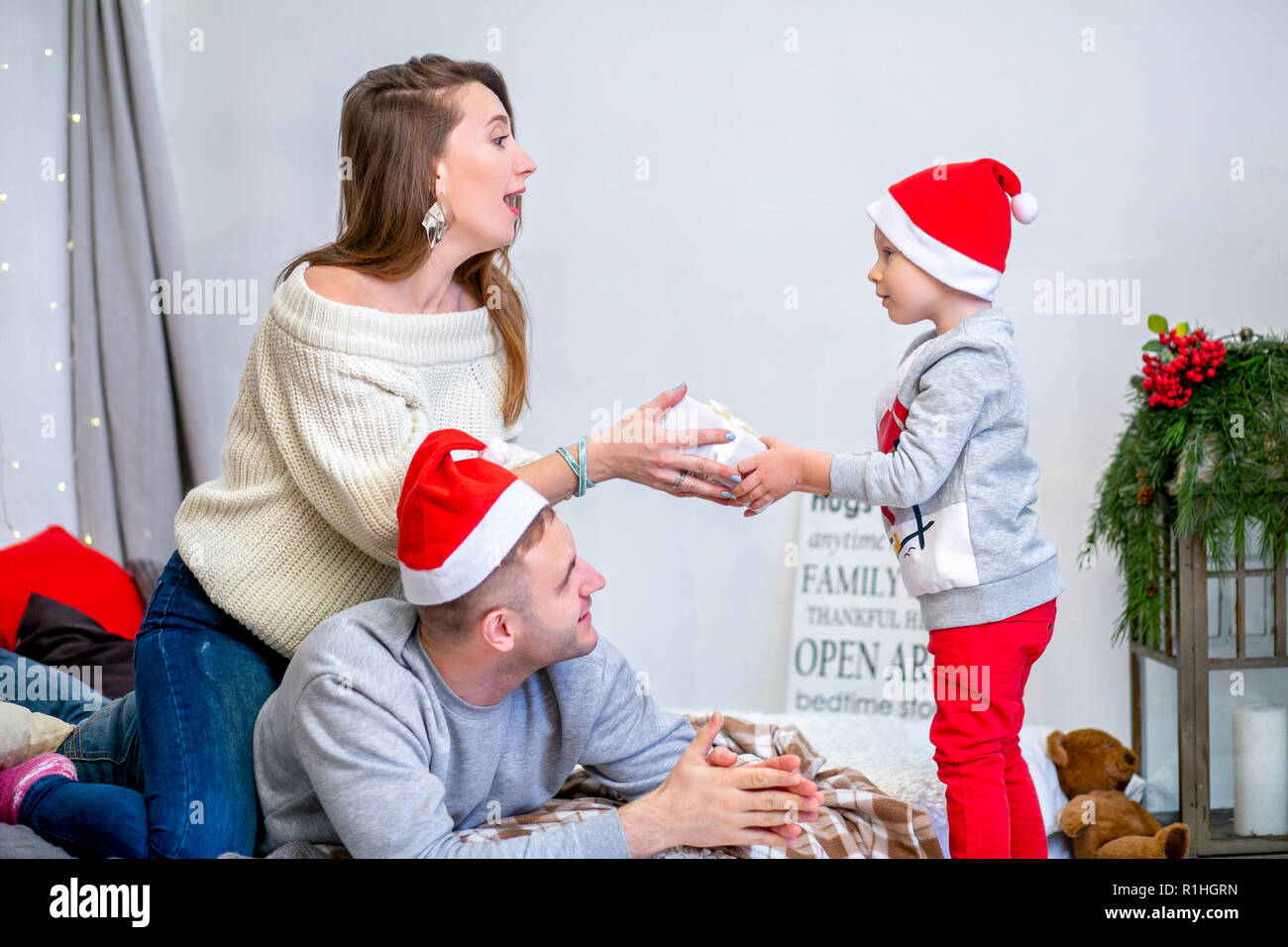 Happy family, father, mother and son, in the morning in bedroom decorated for Christmas. They open presents and have fun. New Year's and Christmas theme. Holiday mood Stock Photo