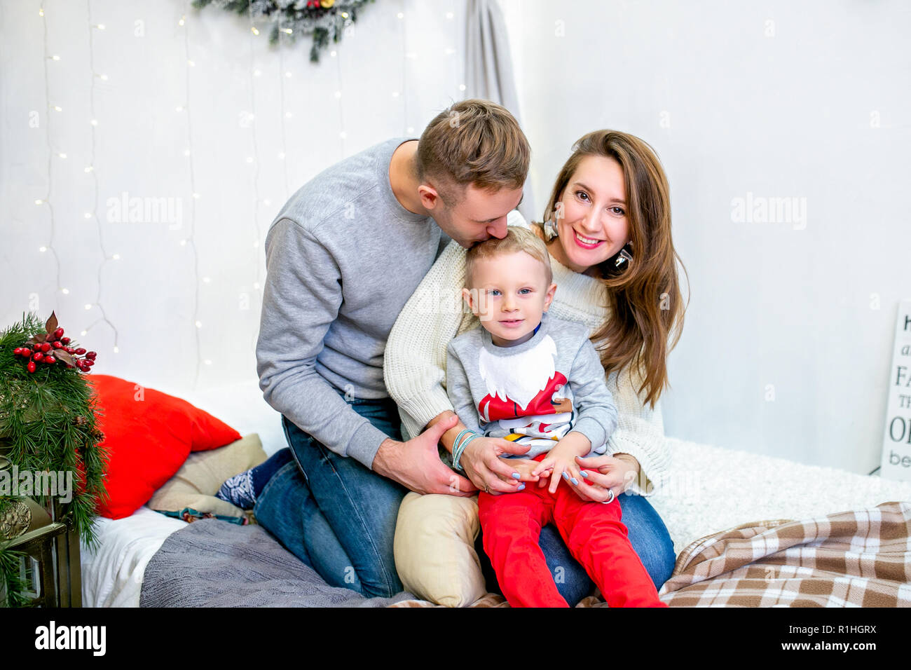 Happy family, father, mother and son, in the morning in bedroom decorated for Christmas. They hug and have fun. New Year's and Christmas theme. Holiday mood Stock Photo