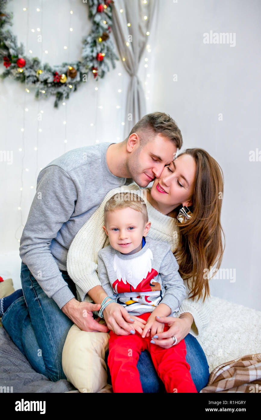 Happy family, father, mother and son, in the morning in bedroom decorated for Christmas. They hug and have fun. New Year's and Christmas theme. Holiday mood Stock Photo