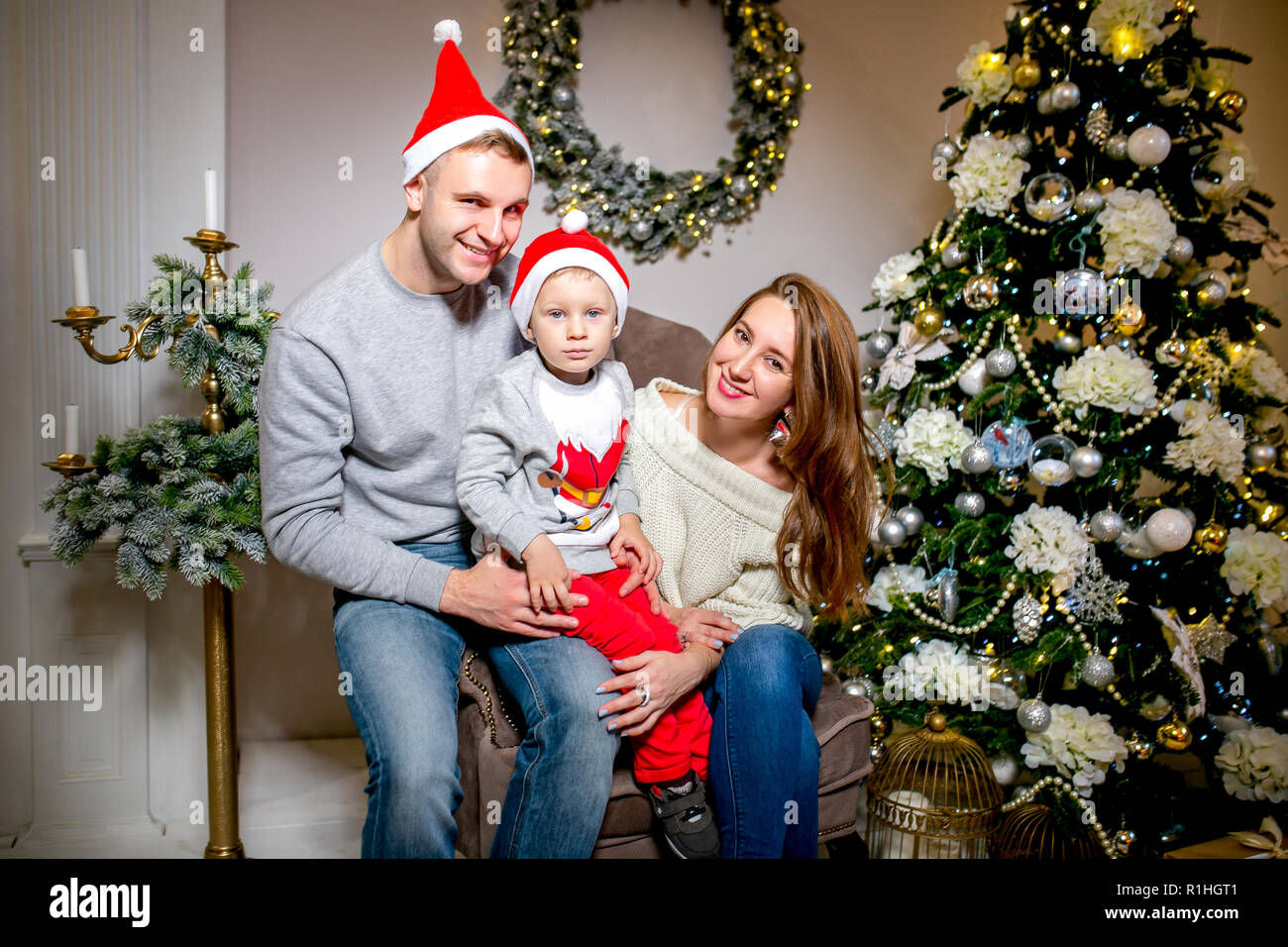 Happy family, father, mother and son, in the morning in living room decorated for Christmas. They open presents and have fun. New Year's and Christmas theme. Holiday mood Stock Photo